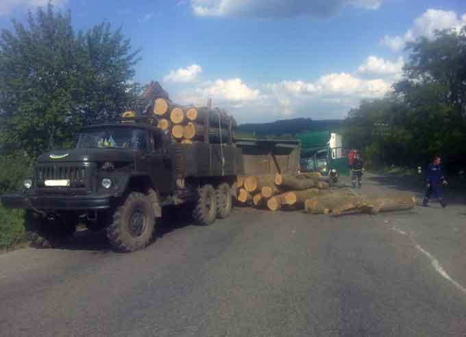 Автомобіль Мерседес, що рухався у попутньому напрямку, зіткнувся із завантаженим колодами причепом вантажівки, який від удару перекинувся.